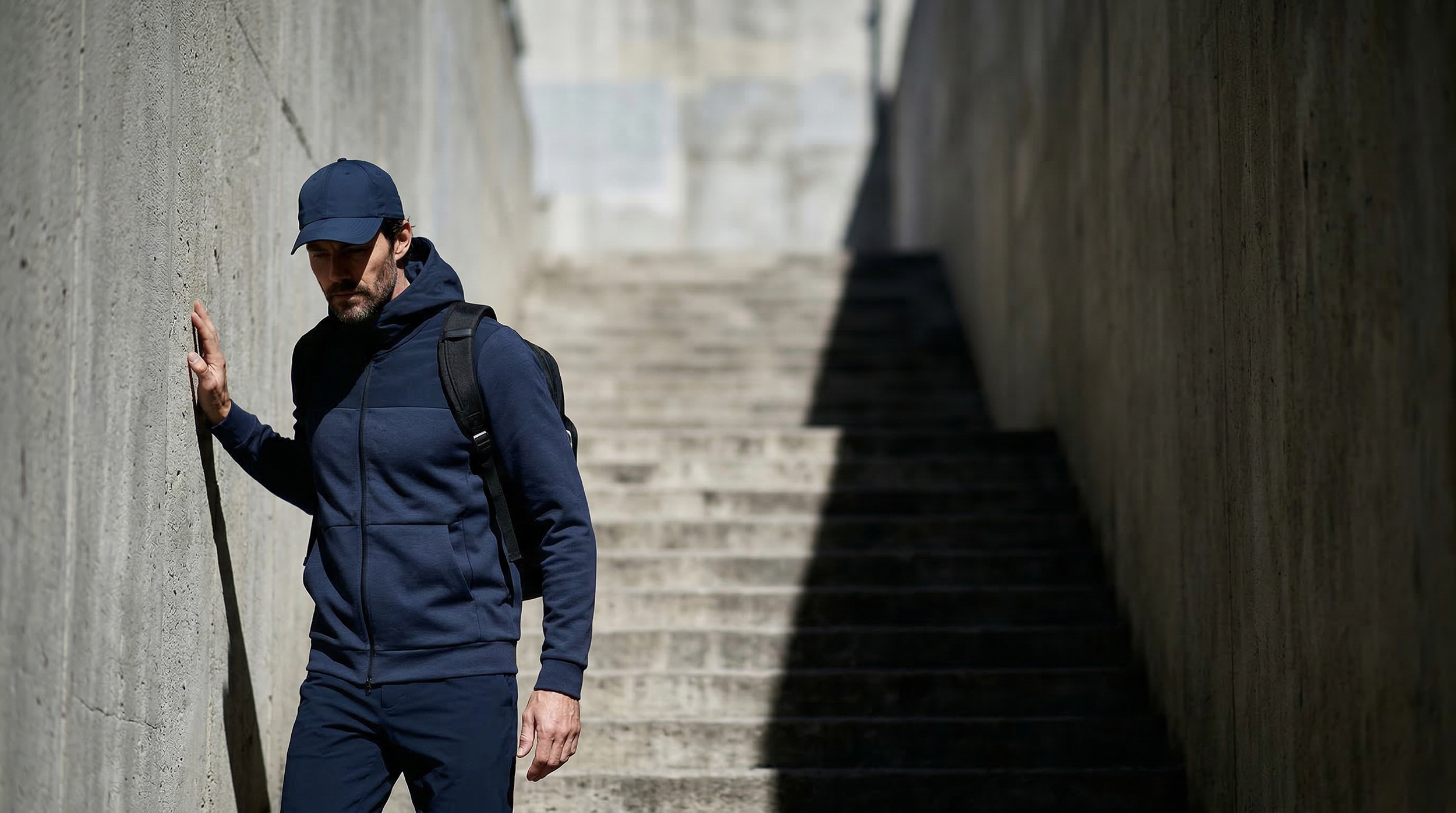 Homme portant un hoodie technique Seagale bleu marine avec sac à dos en milieu urbain.