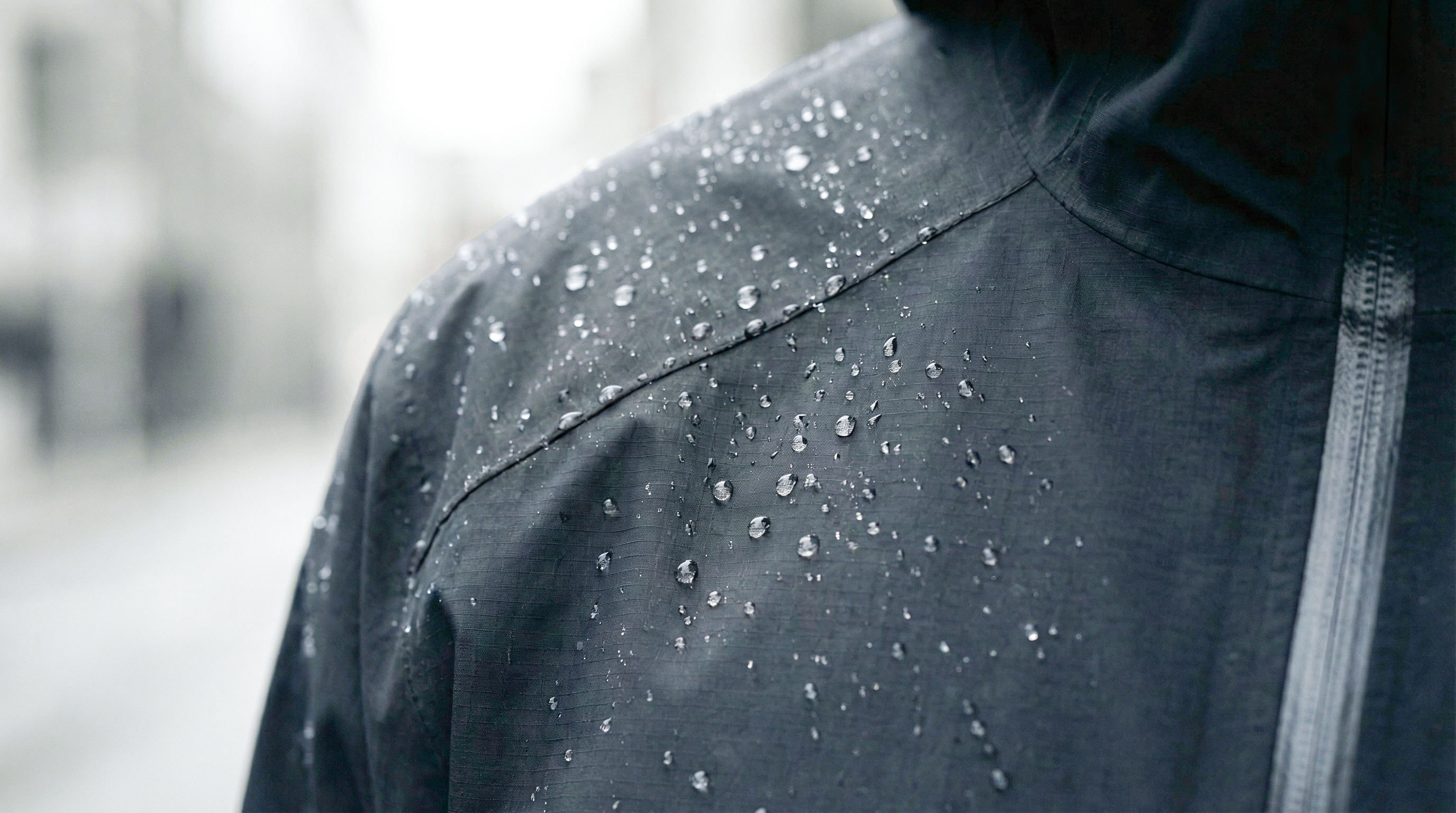 Détail du tissu imperméable de la veste Ultra Hardshell noir avec gouttes d’eau.