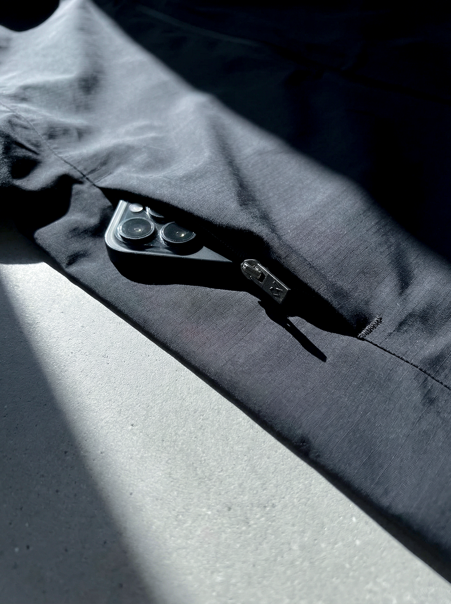 Détail de la poche zippée de la veste Ultra Hardshell noir avec smartphone à l’intérieur.