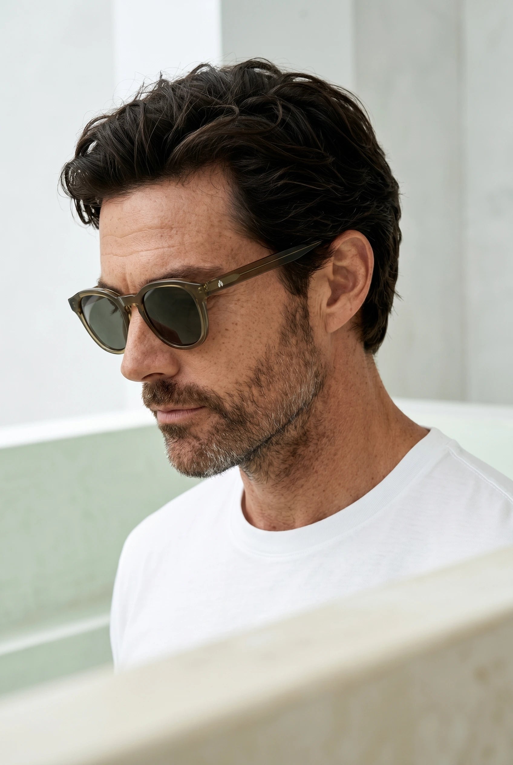 Gros plan sur un homme portant des lunettes de soleil vertes translucides au design intemporel.