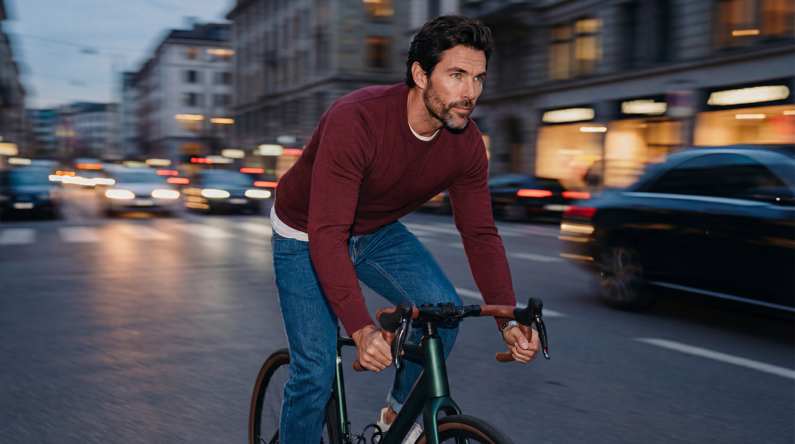 Pullover Ultra Merino en laine mérinos bordeaux porté par un homme à vélo en ville.