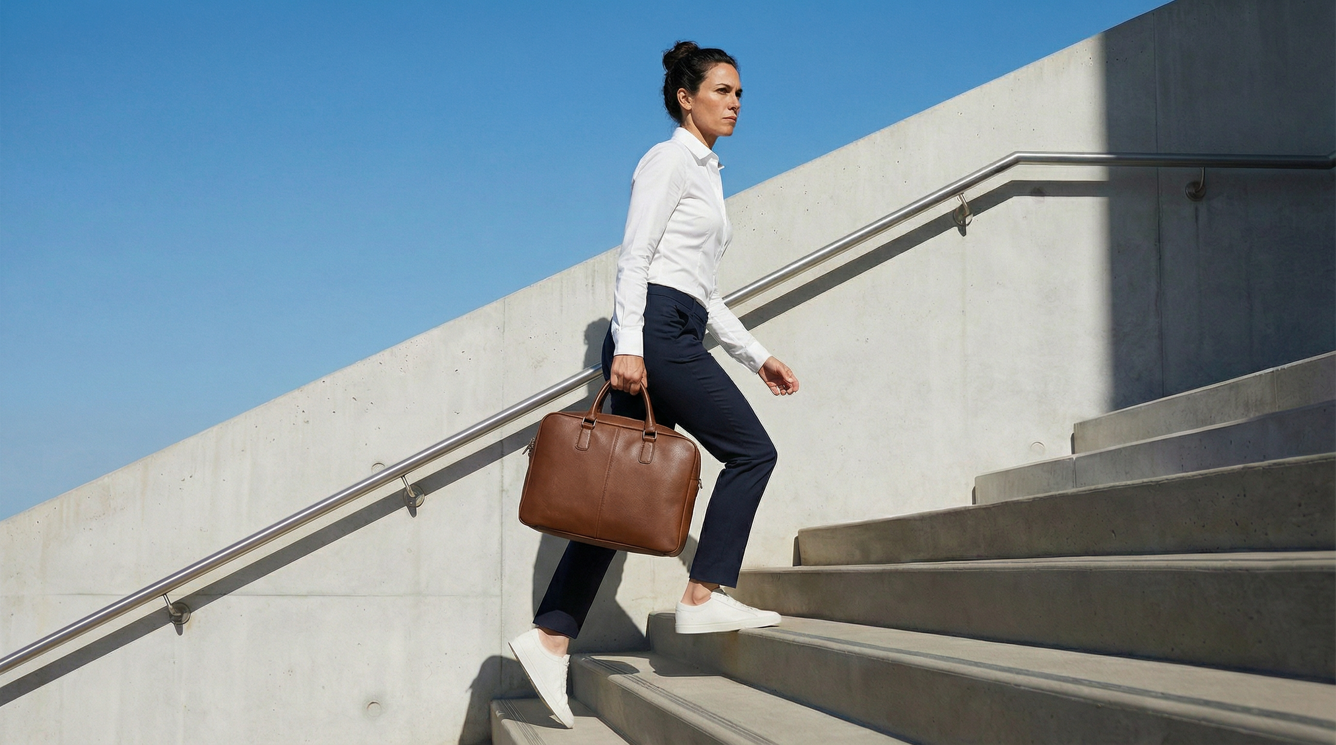 Femme portant une chemise blanche stretch et pantalon bleu marine dans un environnement urbain moderne.