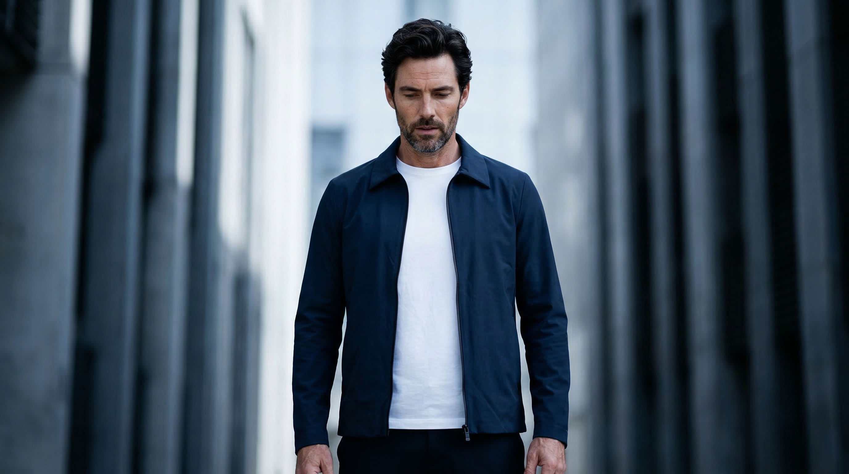 Homme marchant en ville avec veste zippée bleu nuit et t-shirt blanc.